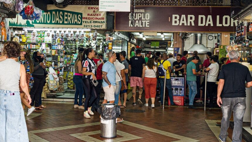 Pessoas em mercado interno, com lojas 'Ponto das Ervas' e bar 'Bar da Lor' com Brahma