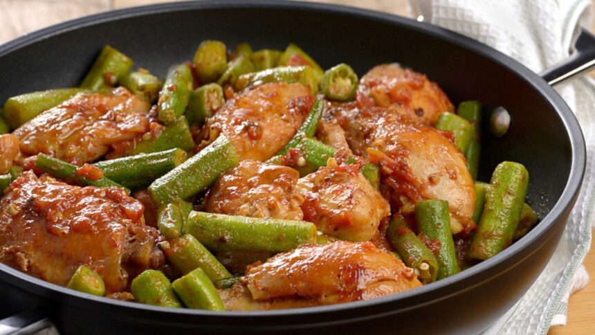 Panela com frango cozido com quiabo verde em molho vermelho e pedaços de tomate
