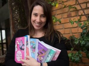 Mulher sorridente de cabelos castanhos segura vários livros coloridos, incluindo "Fazendo meu filme"