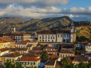 Vista panorâmica de cidade histórica com igrejas, telhados coloniais e montanhas ao fundo