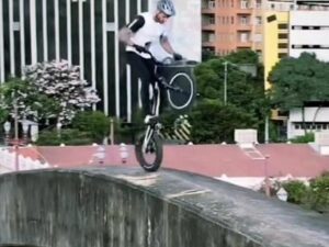 Ciclista em capacete se equilibra em bicicleta trial na borda de viaduto urbano