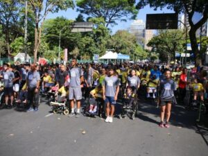 Multidão de pessoas, muitas em cadeiras de rodas, em uma corrida de rua inclusiva