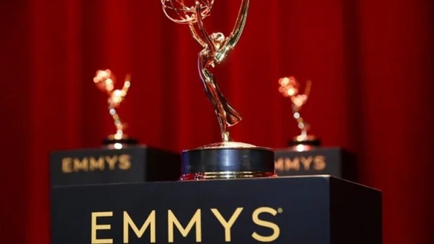 Três troféus dourados do Emmy em pedestais pretos com EMMYS, sobre um fundo vermelho