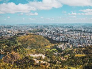 Vista panorâmica de uma cidade grande e morros verdes com um lago sob céu azul