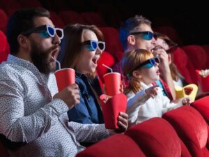 Quatro pessoas assistem filme 3D em cinema, com pipoca e refrigerantes