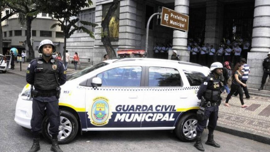 Dois guardas municipais uniformizados e viatura da Guarda Civil Municipal em rua urbana
