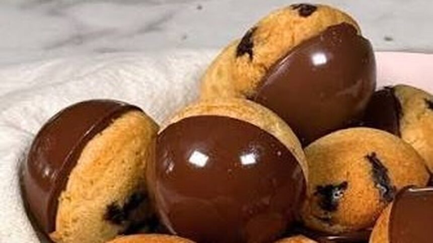 Cookies redondos com gotas de chocolate, metade coberta por chocolate escuro brilhante, sobre pano