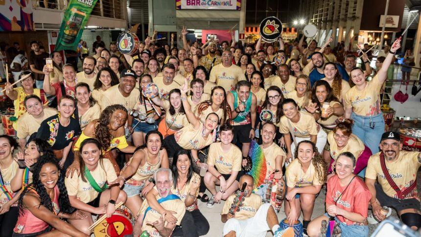 Multidão sorridente em camisas 'Bartucada' com instrumentos de percussão celebra em ensaio noturno
