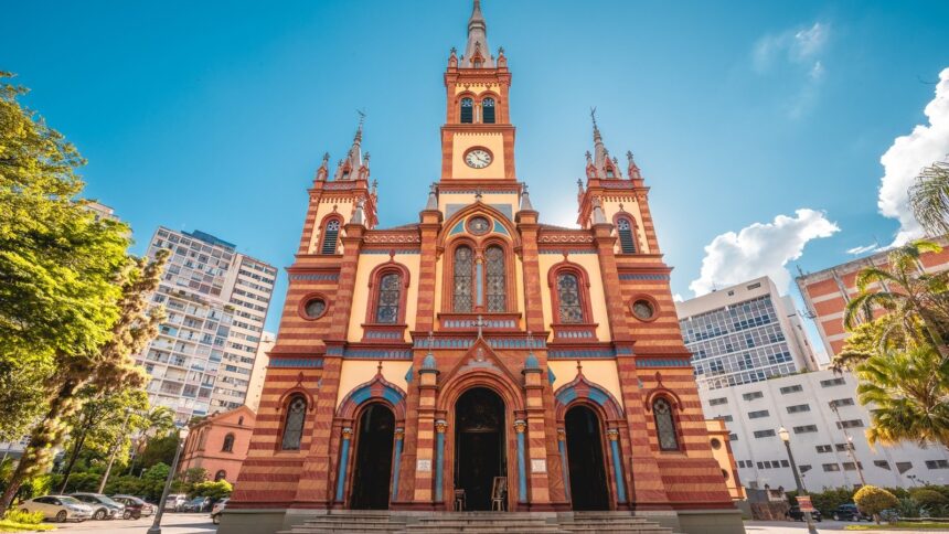 Fachada ornada da Igreja de São José, com torre do relógio, sob céu azul com nuvens