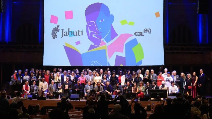 Grande grupo de pessoas no palco em premiação, com logo Jabuti e ilustração colorida de leitor.