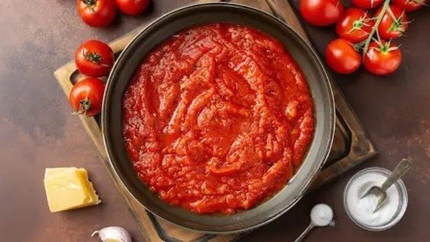 Molho de tomate em tigela cercado por tomates, queijo, alho e bicarbonato de sódio
