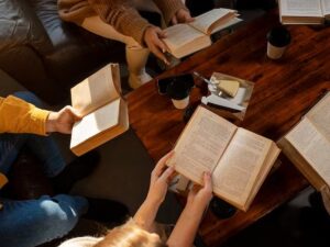 Vista superior de pessoas lendo livros abertos em mesa de madeira com café