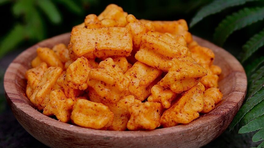 Pequenos pedaços de petisco de tapioca dourados e temperados em uma tigela de madeira