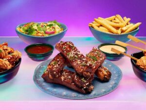 Frango frito, costelas, batatas fritas, salada e espetos coreanos em tigelas coloridas