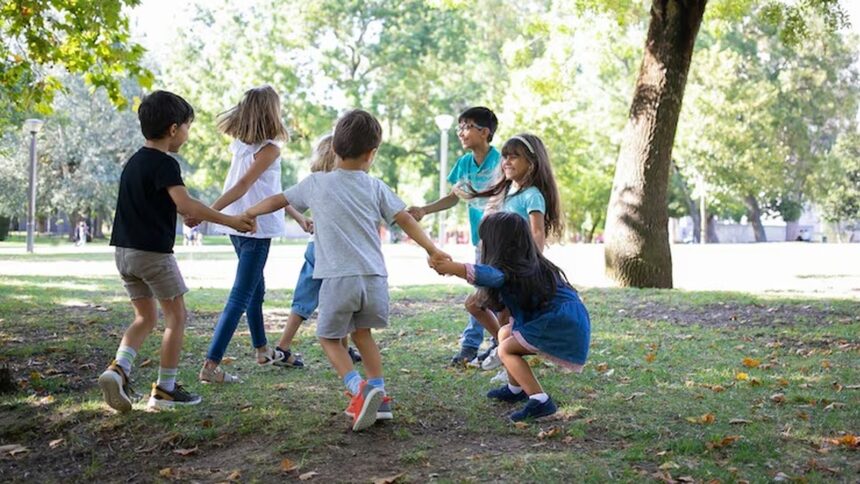 Crianças diversas brincam de roda dando as mãos em parque ensolarado