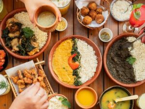 Mesa de madeira com diversos pratos típicos paraenses: maniçoba, camarão, arroz, caldo e bebidas