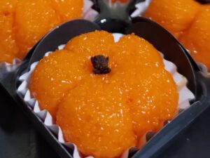 Doce de leite em pó laranja em formato de abóbora com um cravo no topo em forminha escura